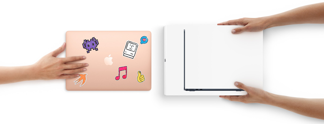 En hånd fører en MacBook med klistermærker på ydersiden hen mod to hænder, der holder en spritny MacBook