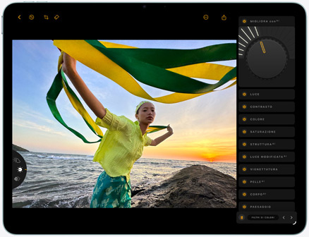 Un iPad Air mostrato di fronte, viene ritoccata la foto di una persona che tiene un tessuto verde e giallo, sullo sfondo si nota una spiaggia al tramonto, sul lato destro si notano gli strumenti di modifica