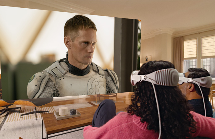 Apple Vision Proを装着した2人がソファに並んで座り、部屋いっぱいに広がるスクリーンに映し出される「マーダーボット」を観ている