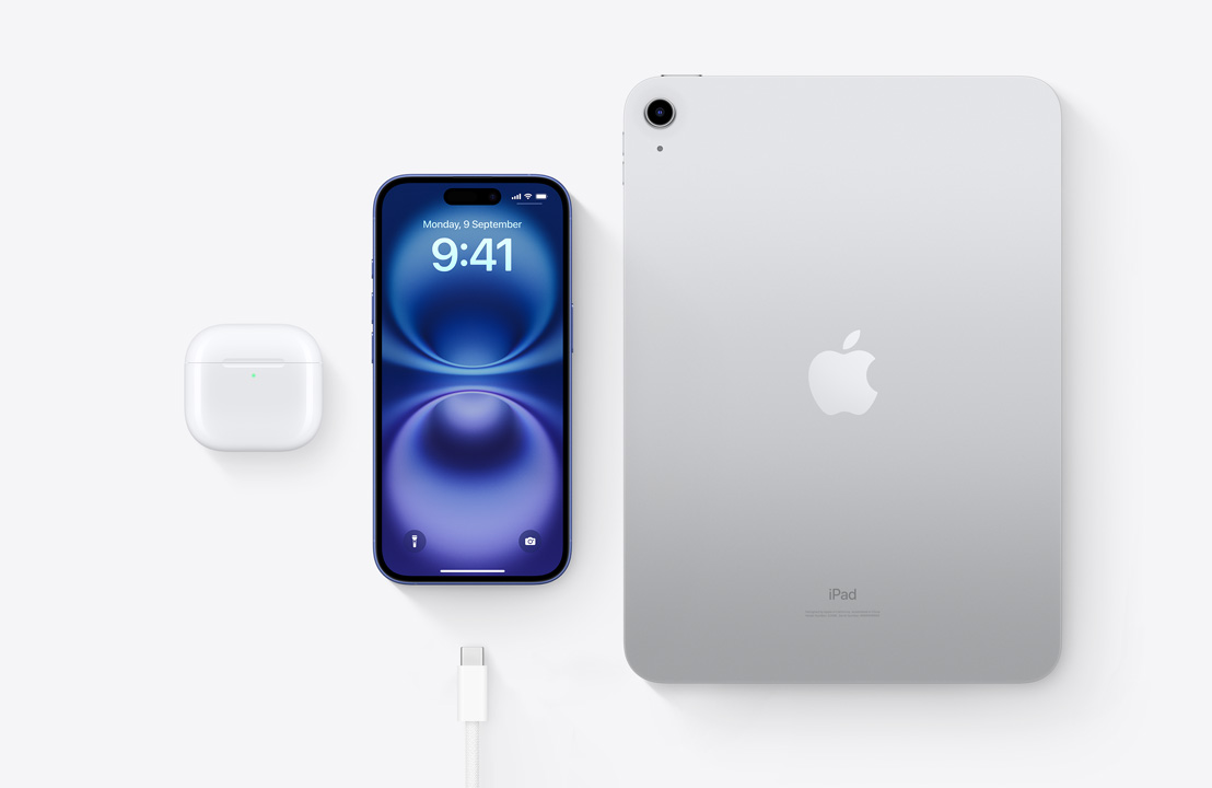 A birds-eye view of AirPods Pro, iPhone 16, and an iPad with a USB‑C connector to demonstrate how all three devices can be charged using the same USB‑C cable.