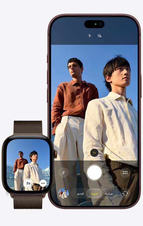iPhone 18 Pro، الجهة الخارجية الأمامية، الكاميرا قيد الاستخدام لالتقاط صورة لرجلين مع خلفية سماء زرقاء، بجانب ساعة Apple Watch Ultra 3 يظهر فيها تطبيق ريموت الكاميرا مفتوحاً