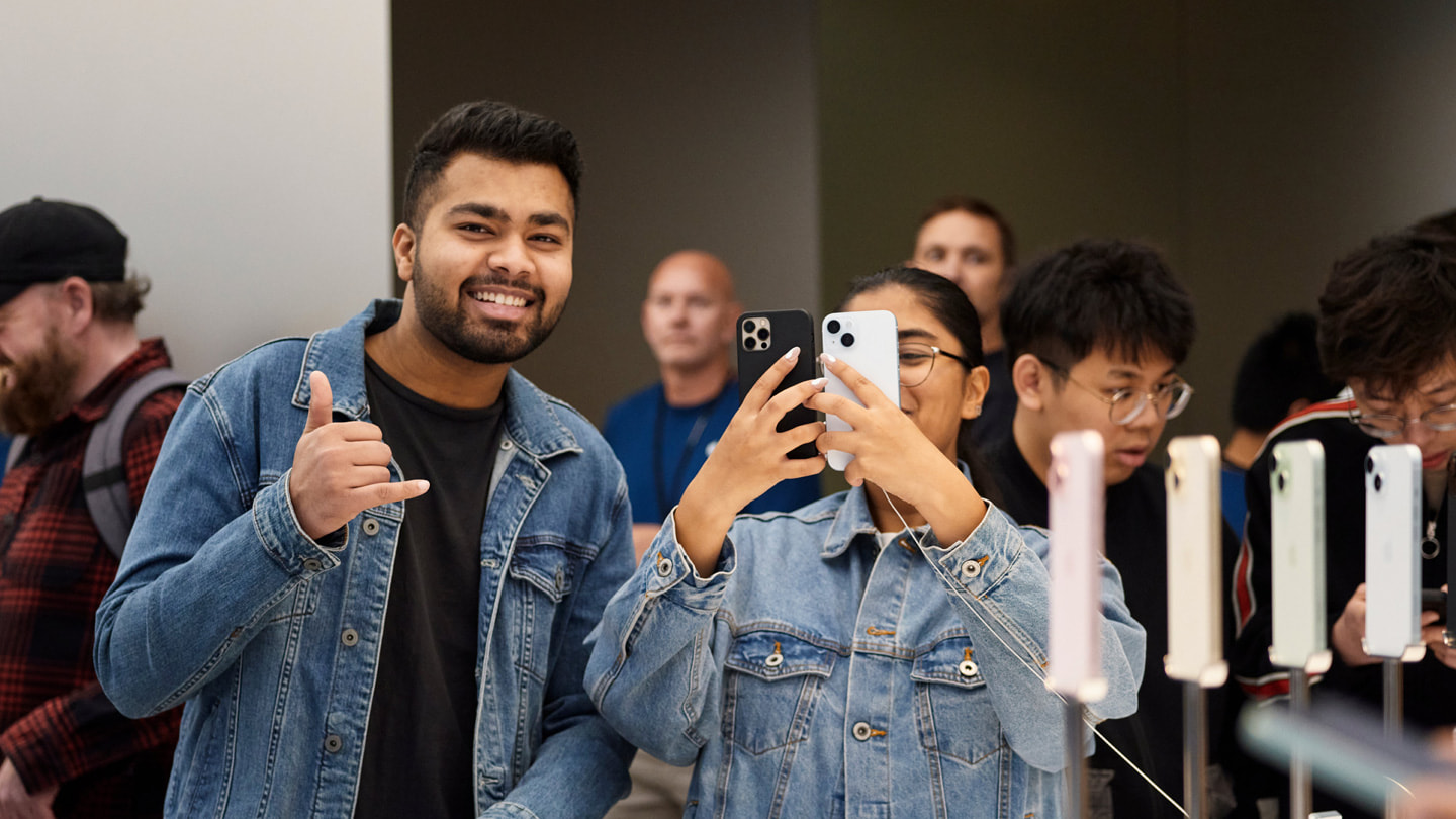 Dva usměvaví zákazníci drží nové iPhony v prodejně Applu v australském Sydney.