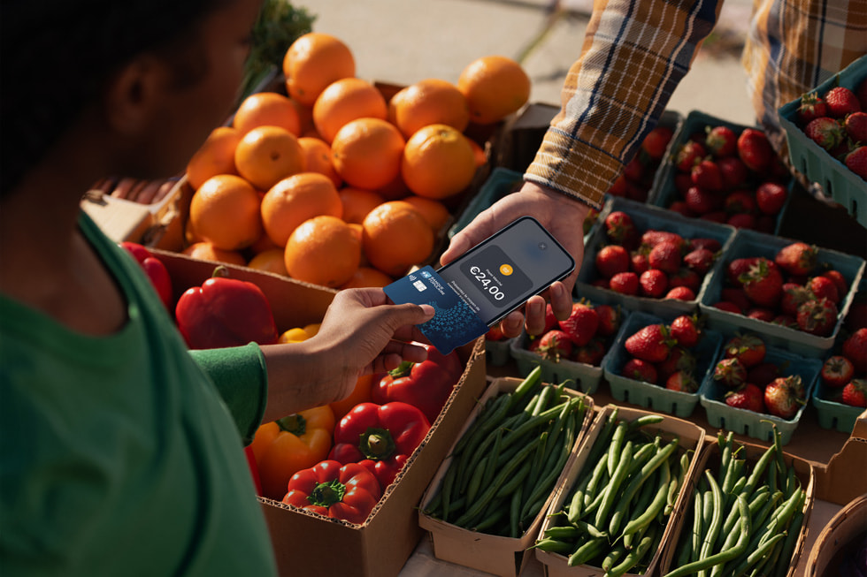 Un commerçant approche son iPhone de la carte bancaire d’une cliente pour effectuer une transaction.
