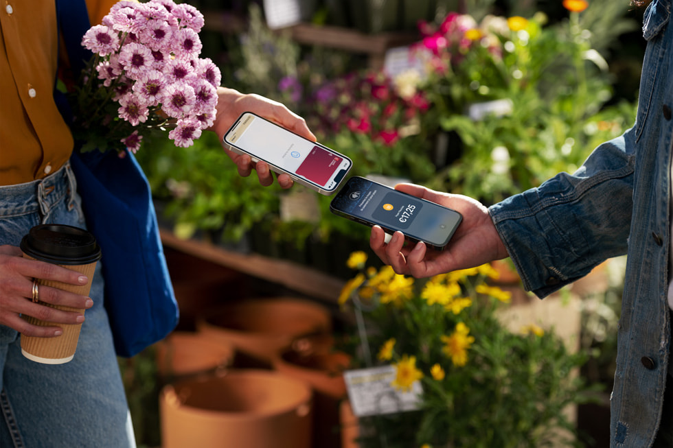 Une cliente et un commerçant approchent leurs iPhone respectifs afin de procéder au paiement.