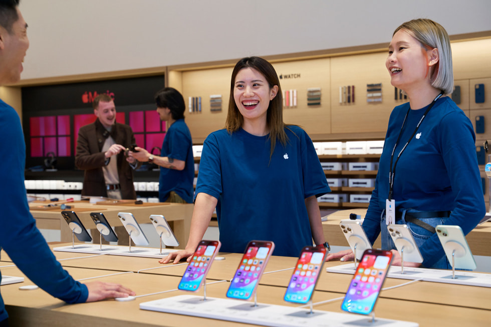 Drei Teammitglieder an einen Tisch mit der aktuellen iPhone Familie.
