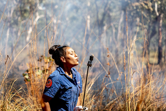 Josephine Austral apaga la antorcha de goteo tras realizar una quema de suelo en la zona de gestión de tierras de Mimal Land.