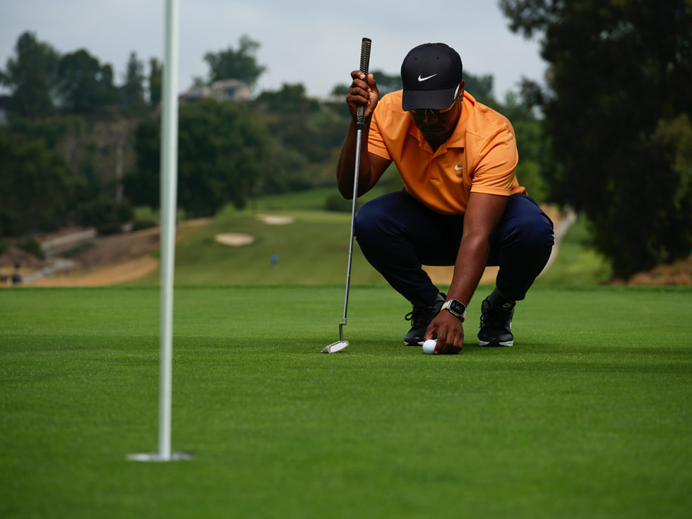 Hình ảnh một golf thủ đeo Apple Watch đang ở tư thế chuẩn bị thực hiện cú gạt nhẹ bóng (putt).