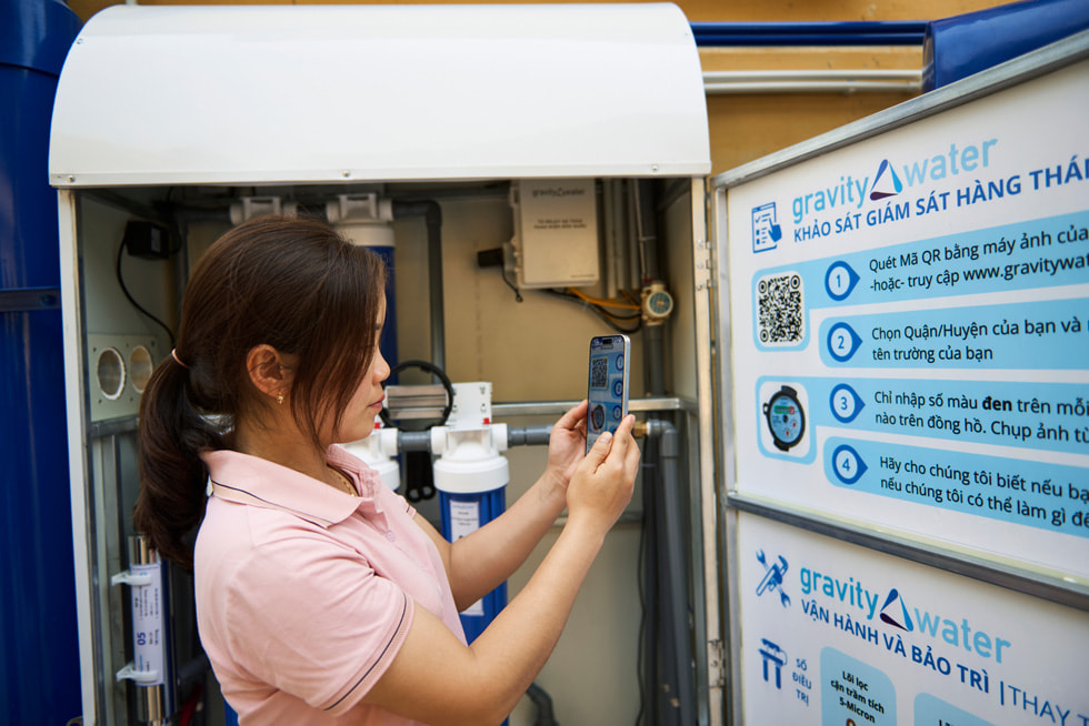 Een leerling scant met een iPhone een QR-code op een informatiebord van Gravity Water op de kostschool in Vay Nua.