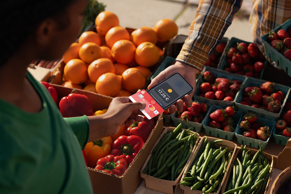Ein Kunde hält seine Karte neben das iPhone eines Händlers, um die Transaktion auf einem Wochenmarkt abzuschließen.
