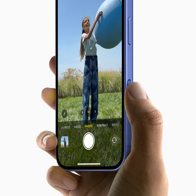 Bir kullanıcı iPhone 16 ile bir top tutan kişinin fotoğrafını çekiyor.