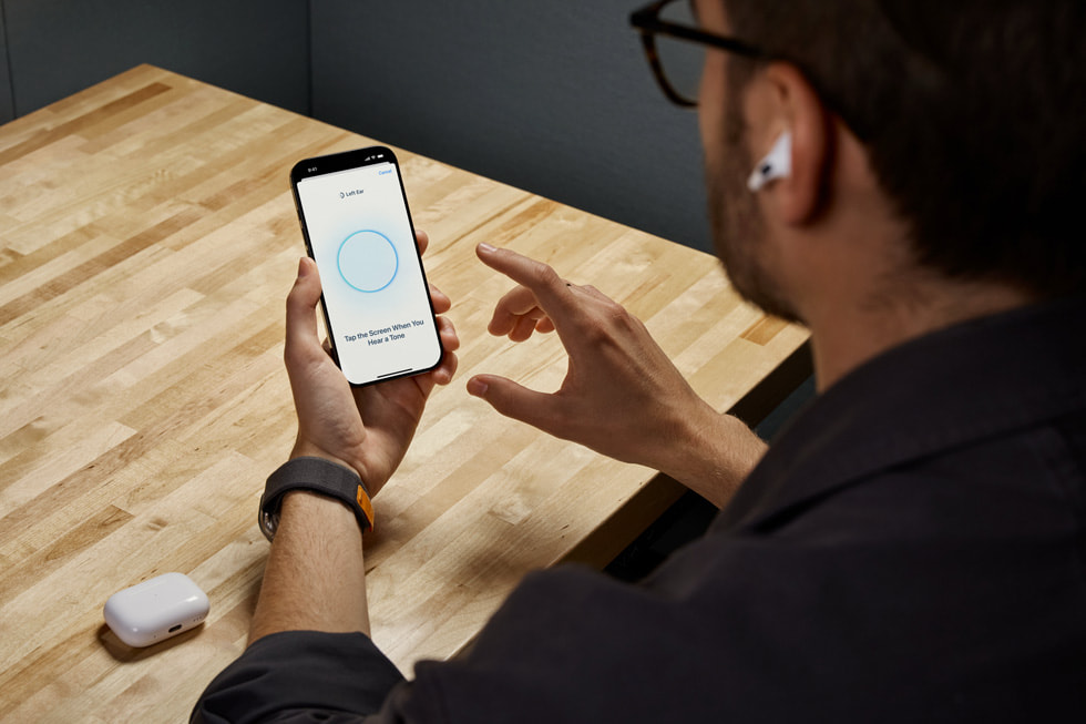 iPhoneを持って新しいヒアリングチェック機能を使っているAirPods Pro 2のユーザー。