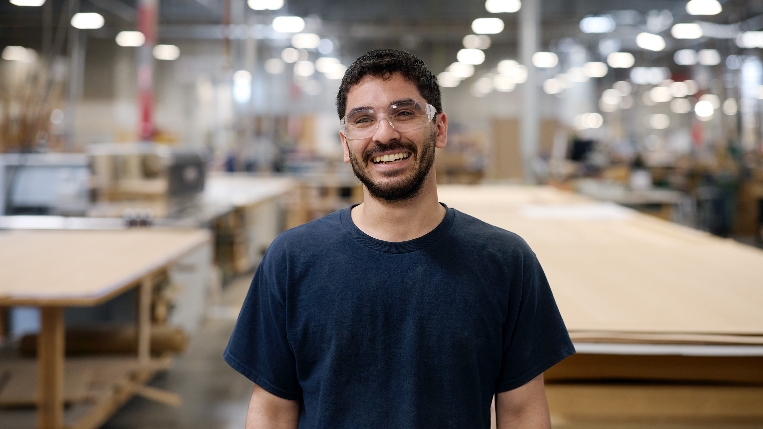 A supplier employee wearing protective eyewear works in a factory-like setting.