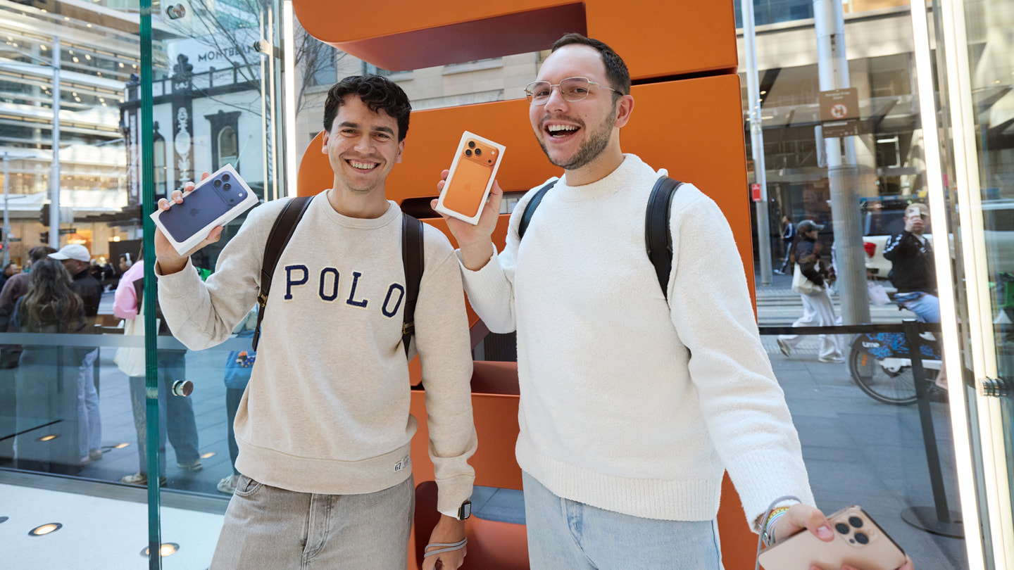 澳洲雪梨的 Apple Sydney 零售店裡兩位笑容滿面的顧客，與新購的 iPhone 17 Pro 合影。