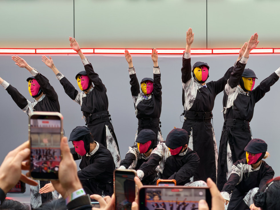 Bailarines con máscaras naranjas y rojas bailan en Apple Taikoo Li Chengdu, en China.