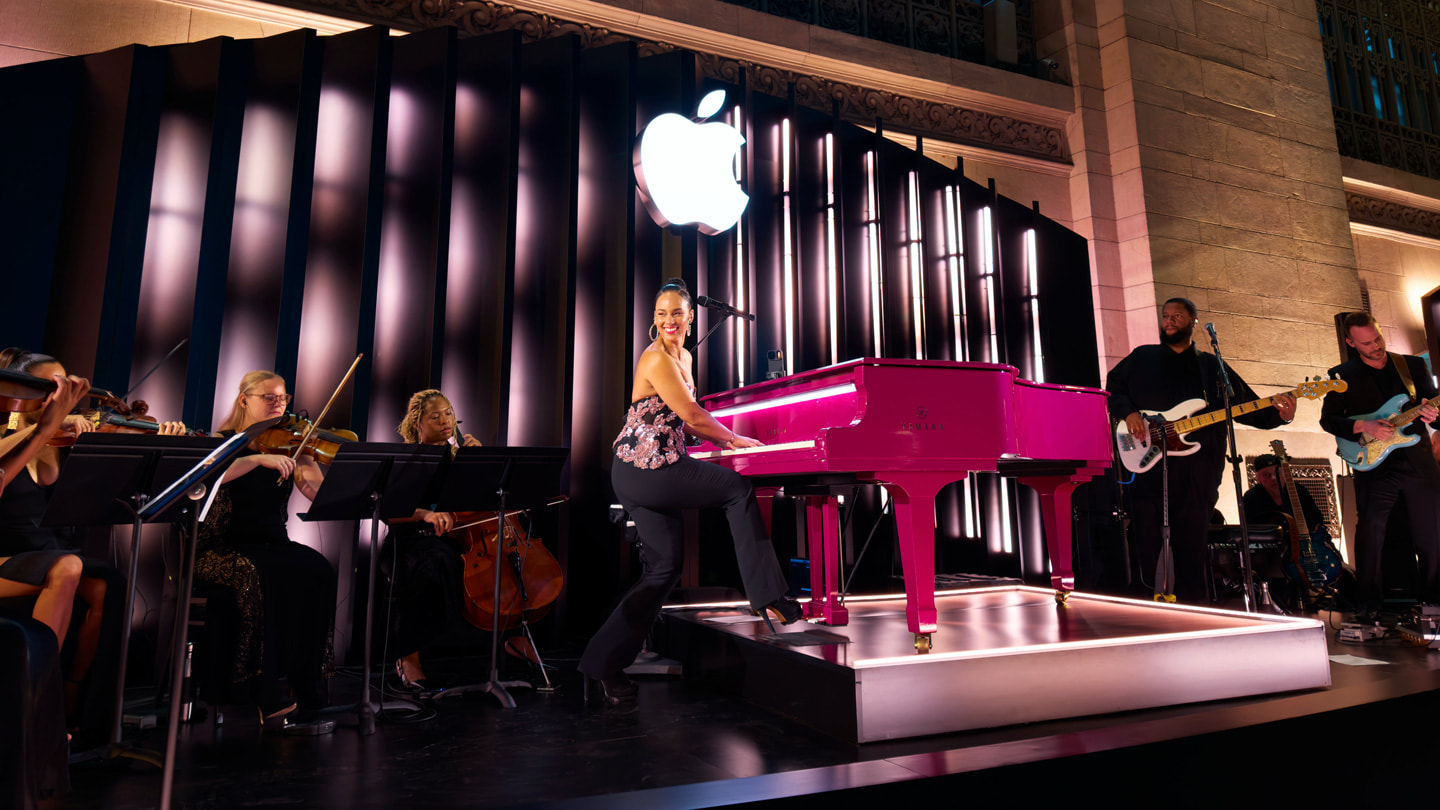 Alicia Keys toca el piano en el escenario de Apple Grand Central, rodeada de músicos.
