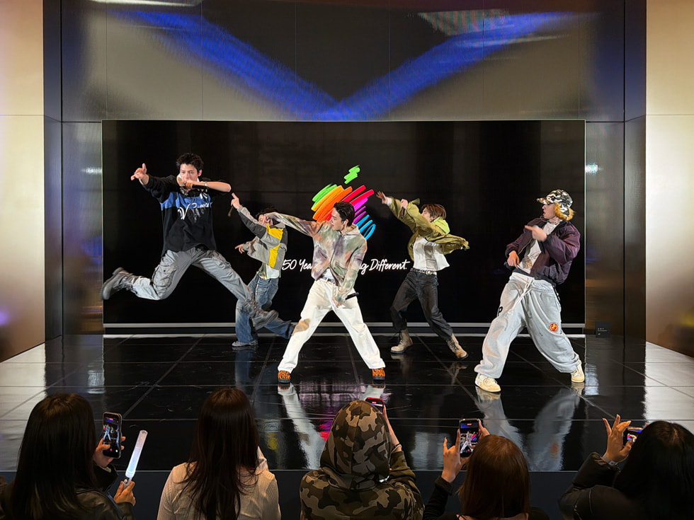 Los integrantes de la banda CORTIS fotografiados durante una coreografía en un escenario de Apple Myeongdong, en Seúl, con uno de ellos captado en pleno salto.