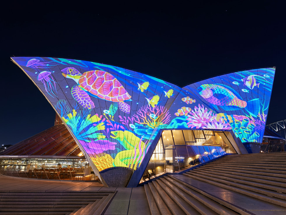 Proyección de la artista Rebecca Mills en las bóvedas de Bennelong que muestra a una tortuga en un arrecife lleno de colores.