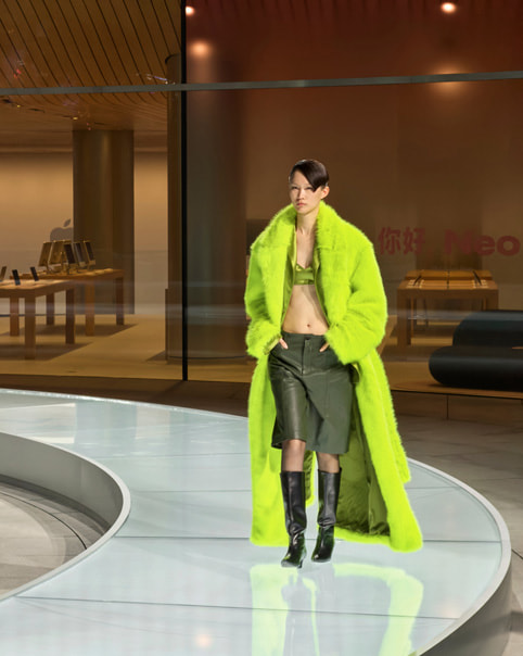 Una persona vestida de verde desfila en una pasarela circular en Apple Jing’an.