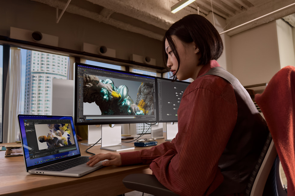Una persona usa un monitor Studio Display XDR y una MacBook Pro en un entorno de oficina.
