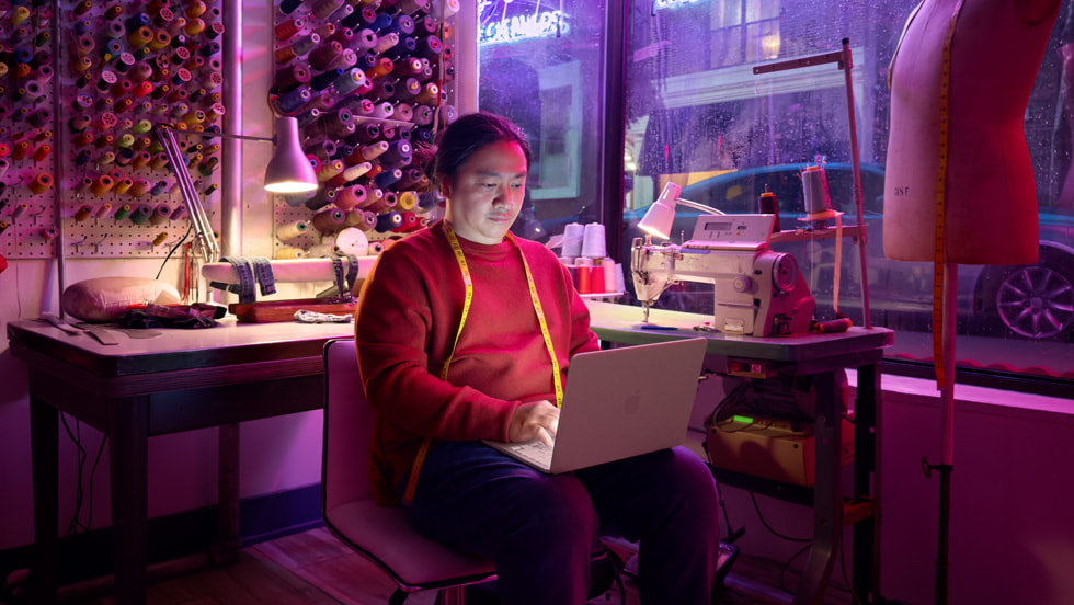 Una persona en un estudio de confecciones trabaja en una MacBook Neo.