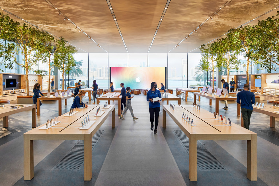 أعضاء فريق العمل في متجر Apple بجزيرة المادية يعدّون طاولات العرض داخل المتجر.
