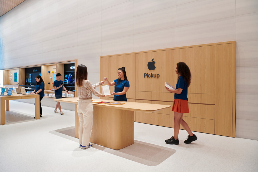 Een Apple medewerker overhandigt een tas aan een klant in het gedeelte voor ophalen in Apple Brompton Road.