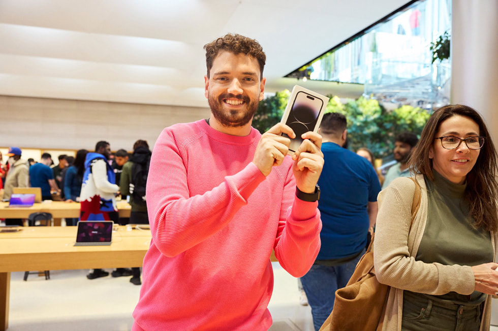 En glad kund poserar med nya iPhone 14 Pro. 