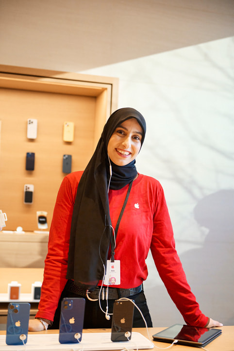 Một Chuyên Gia Apple đứng cạnh bàn trưng bày iPhone trong Apple Pacific Centre mới tại Vancouver, Canada.