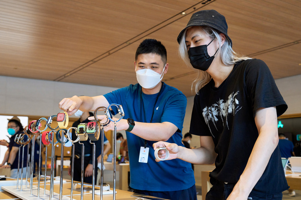 En Apple Sanlitun-medarbetare visar Apple Watch-enheter för en kund.