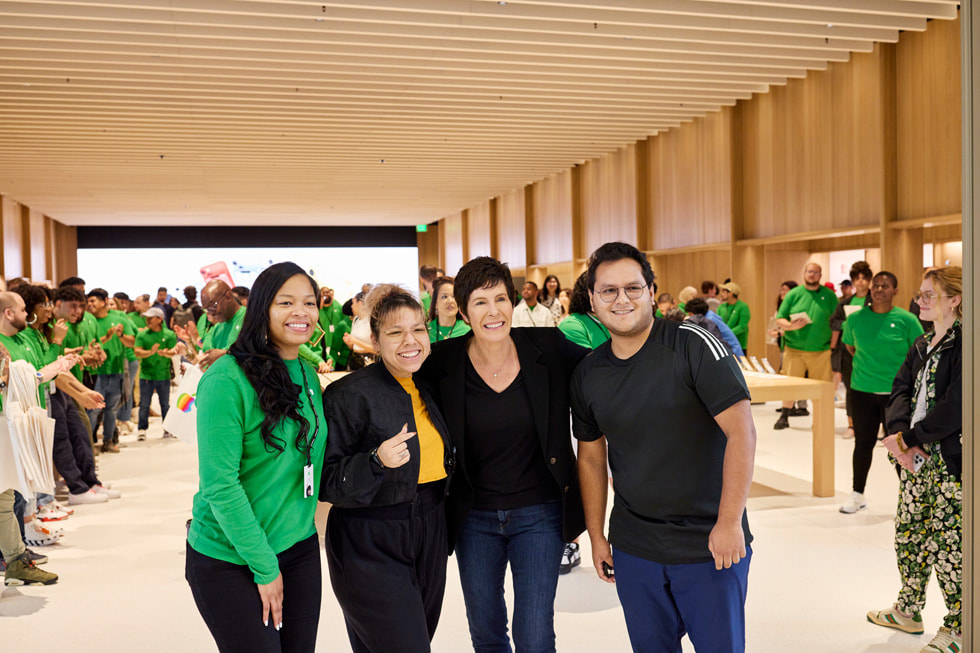 En Apple-medarbetare, en kund, Deirdre O’Brien och ytterligare en kund poserar framför kameran på återinvigningen av Apple Tysons Corner.