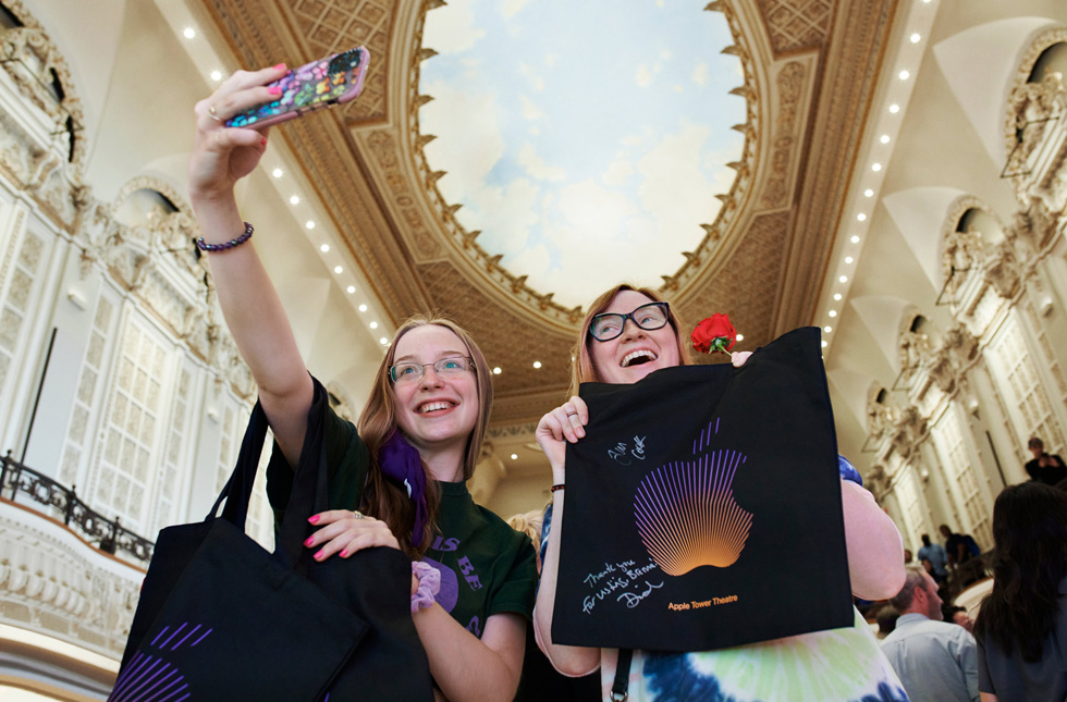 Kunder tager en selfie med deres nyindkøbte Apple-produkter under hvælvingen i Apple Tower Theatre, der er malet som himlen.