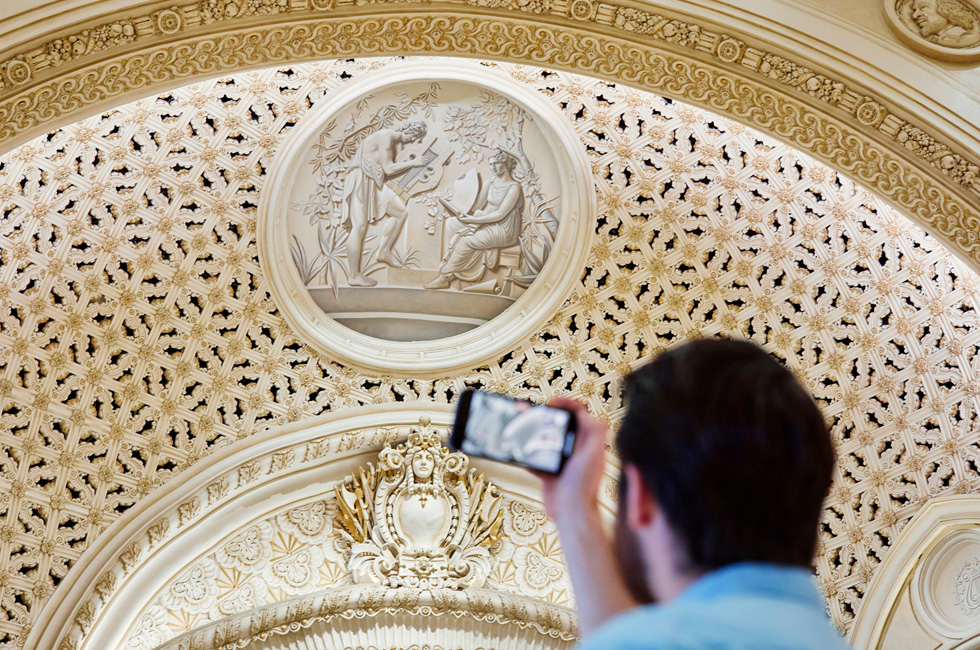 En kunde tager et billede af de dekorative detaljer i Apple Tower Theatre med sin iPhone.