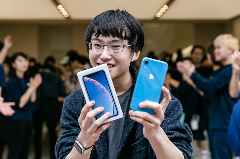 ブルーのiPhone XRとパッケージを掲げて見せるお客様。