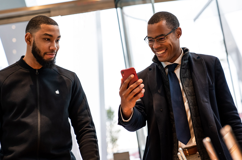 iPhone XR PRODUCT(RED)を手にしたお客様に接客しているApple Downtown Brooklynのチームメンバー。