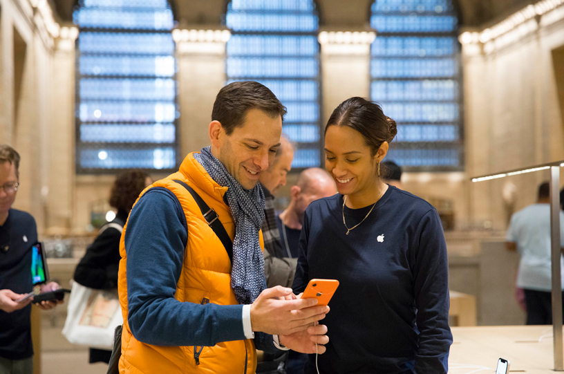iPhone XRを手にしたお客様を接客しているApple Grand Centralのチームメンバー。