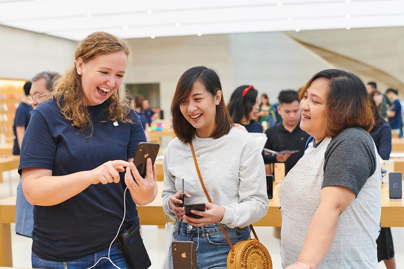 2人のお客様にiPhone XRを見せているAppleのチームメンバー。