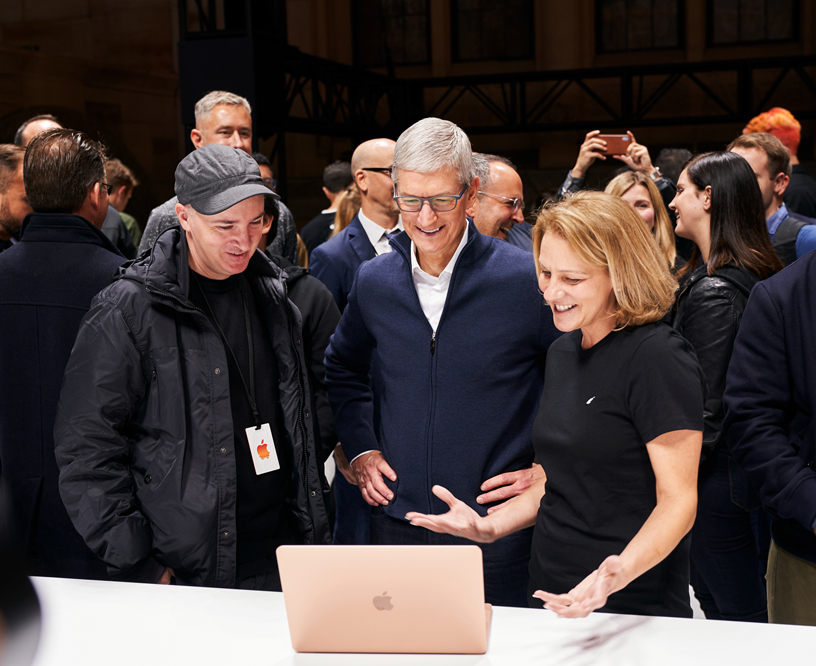 KAWS ve Tim Cook, bir Apple ekip üyesiyle birlikte MacBook Air’i inceliyor.
