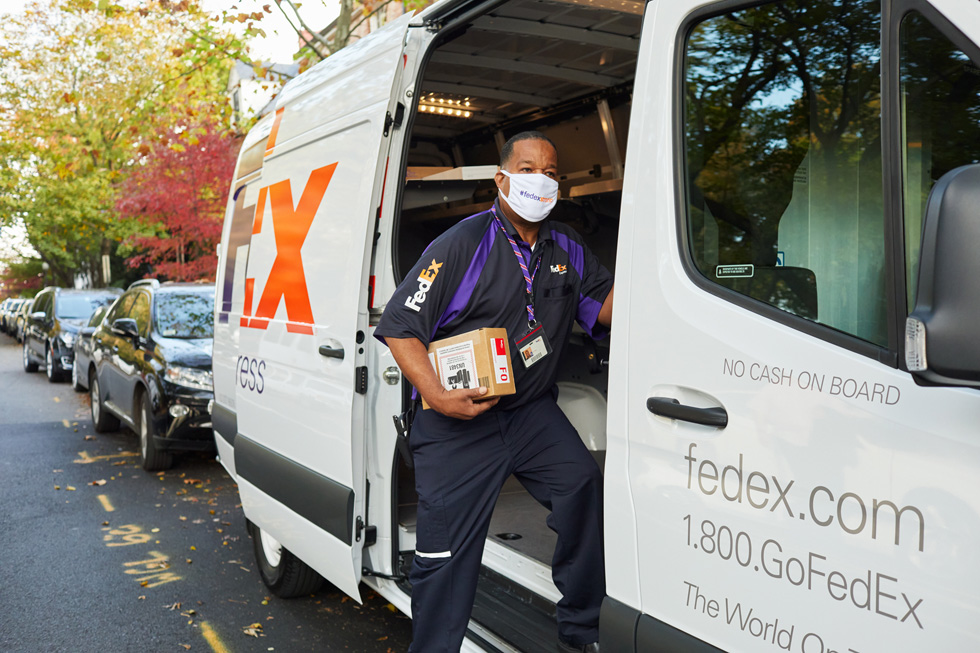 FedExデリバリーバンからAppleのパッケージをお客様に届けるFedExの配達員。
