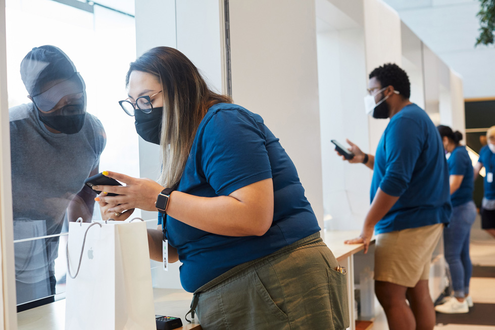 Apple Highland Villageでお客様がApple製品を購入するのを手伝うAppleの従業員。