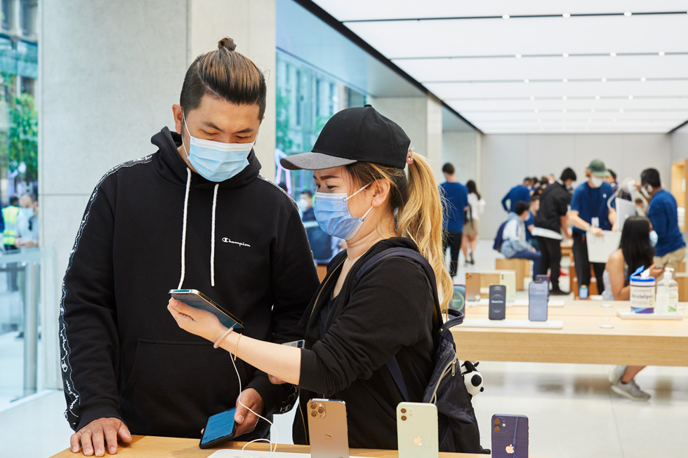 Apple Sydneyのディスプレイテーブルで新しいiPhone 12 Pro Maxを試すお客様。