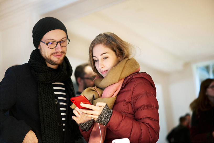 İki müşteri kırmızı iPhone XR’ı kullanıyor.