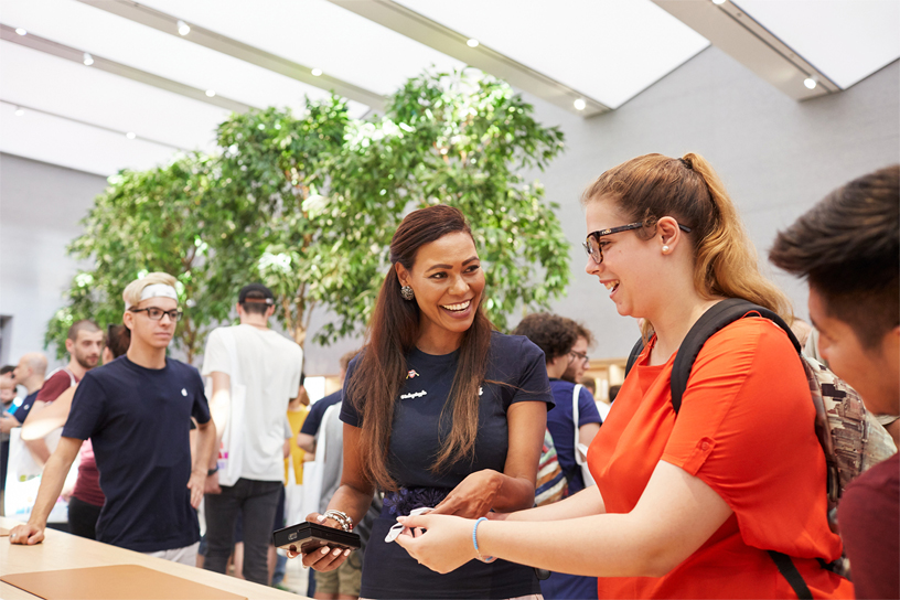 إحدى أعضاء فريق العمل في Apple Piazza Liberty تضحك مع إحدى الزائرات.