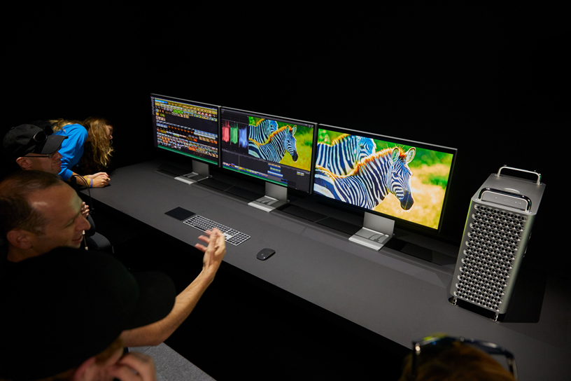 Mac Pro와 나란히 배치된 세 대의 Pro Display XDR 화면을 살펴보고 있는 WWDC 참가자.