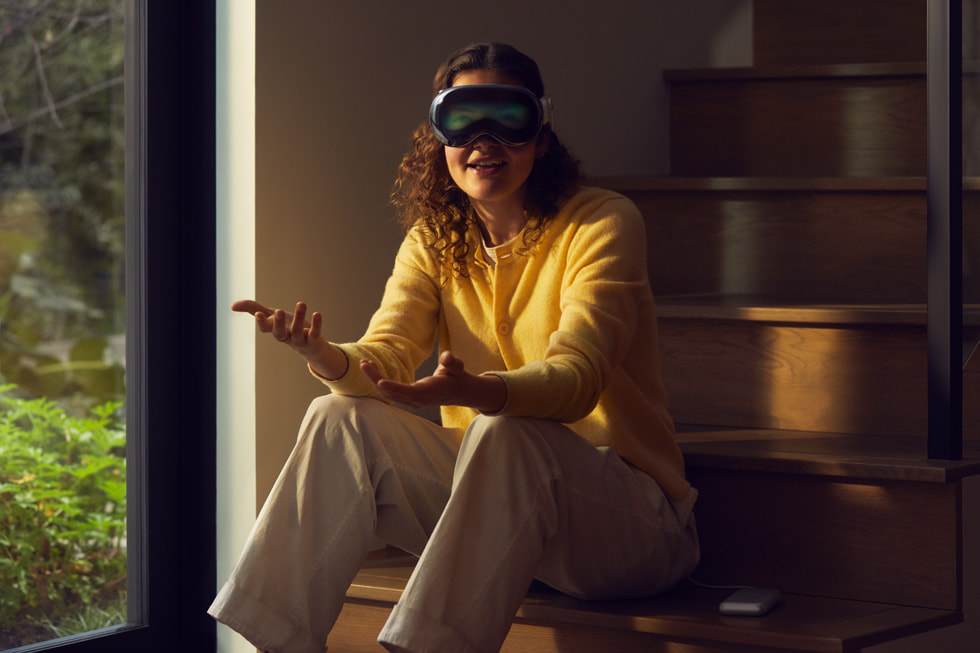 Una persona sentada en las escaleras de su casa teniendo una conversación en Apple Vision Pro.