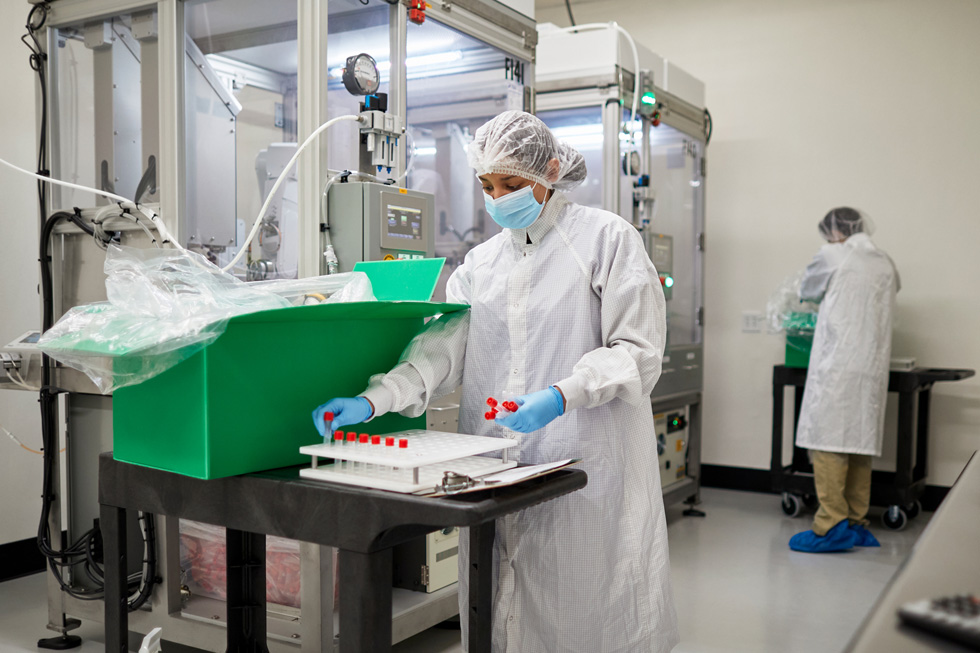 إحدى العاملات بشركة COPAN Diagnostics تضع قوارير العينات على صينية العينات.