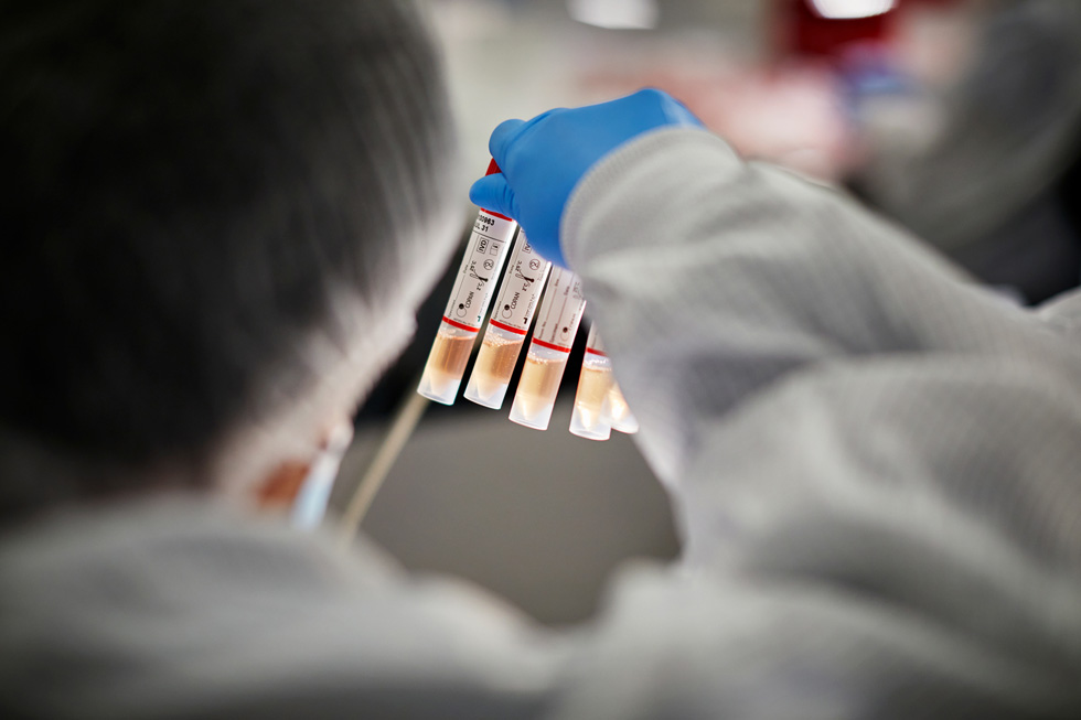 عامل مختبر في COPAN Diagnostics يتفحص قوارير العينات.