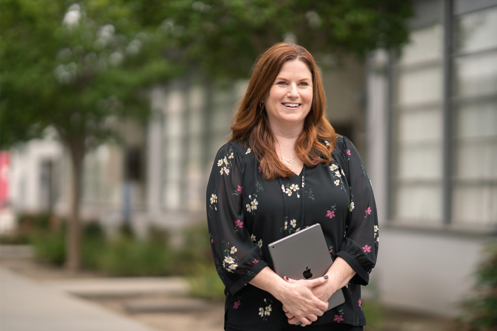 Downey Unified 初等教育主任兼 Apple Learning Coach Jennifer Robbins 手持 iPad 站在室外。