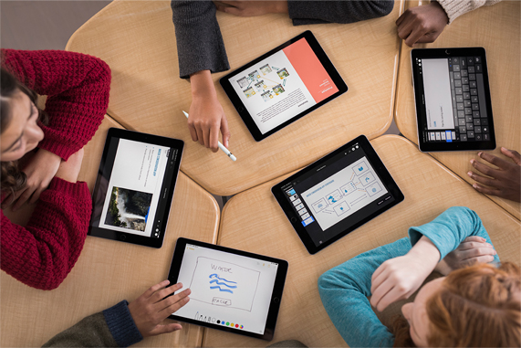 Bir masada iPad kullanan küçük öğrenciler. 