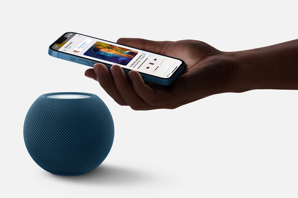 HomePod mini i blå som samarbeider med iPhone om å overføre musikken.
