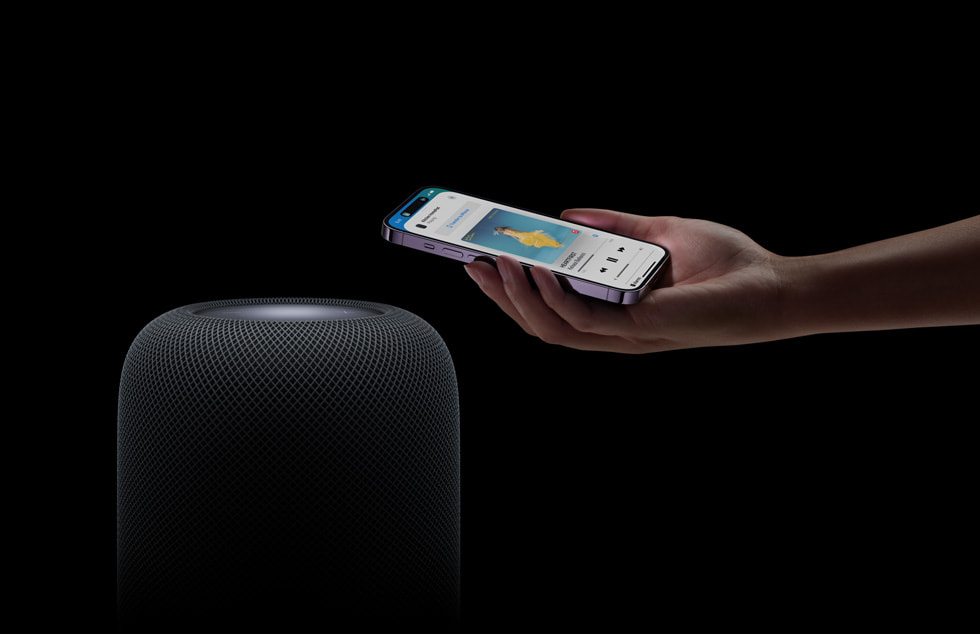 HomePod’un (2. nesil) üzerinde elinde iPhone tutan bir kullanıcı.